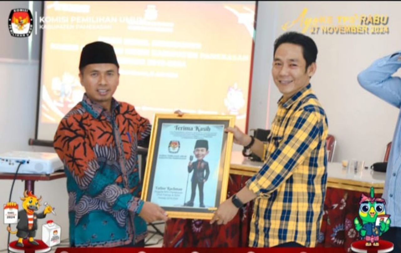 Foto : Dr. Fathorrahman, mantan komisioner KPU Pamekasan terima kenang-kenangan dari Mahdi, Ketua KPU yang baru. (Sumber foto : dok KPU Pamekasan) .