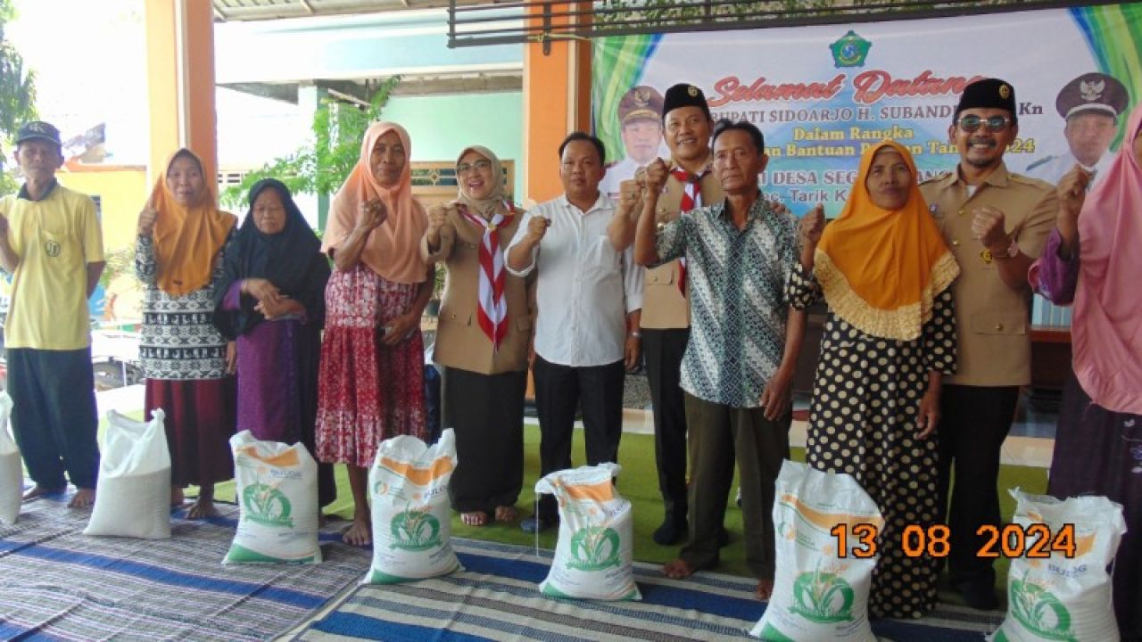 Plt Bupati Subandi didampingi Kades Segodobacang saat penyaluran bansos pangan beras. (Ist)