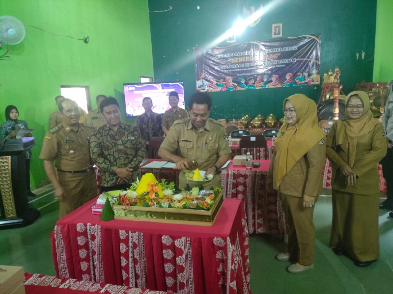 Plt Asisten I Drs.Rully Wahyu Prasetyowanto, M.E sedang memotong Tumpeng sebagai penanda Pembukaan KBM " Generasi Emas" di Desa Sragi.. (ist)