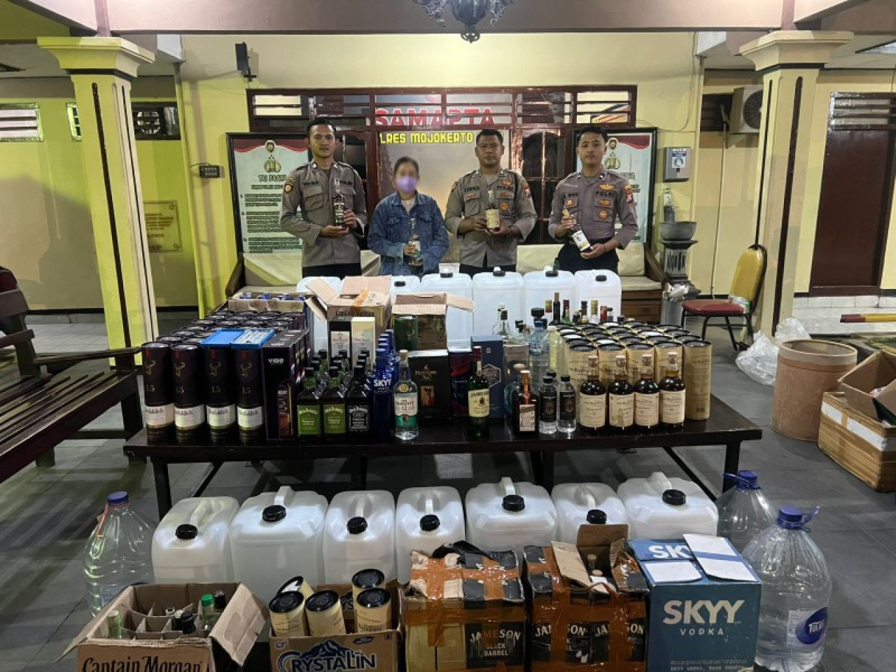 Anggota Satsamapta Polres Mojokerto Kota bersama barang bukti miras oplosan berbagai merk wanita pemilik pabrik. (ist)