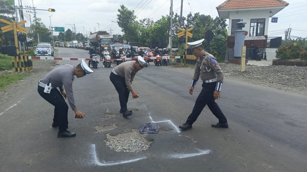 Anggota Satlantas Polres Mojokerto Kota tandai jalan berlubang untuk hindari kecelakaan. (ist)