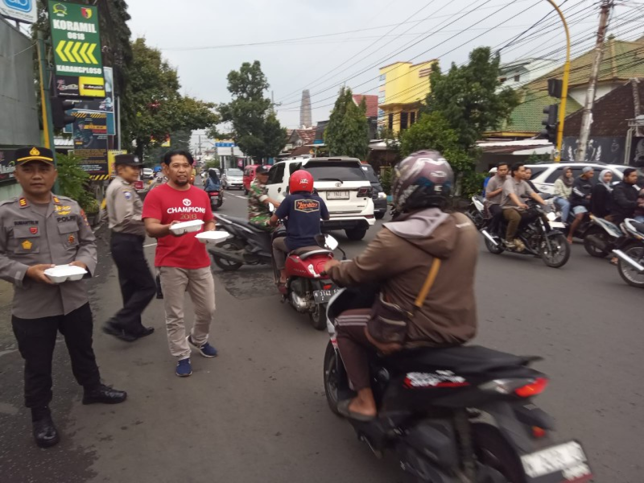 Petugas Polsek Karangploso saat berbagi takjil kepada pengguna jalan. (ist)