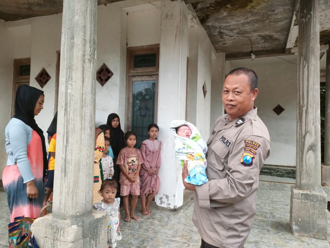 petugas Polres Sampang menggendong bayi yabg ditemukan warga di sawah. (ist)