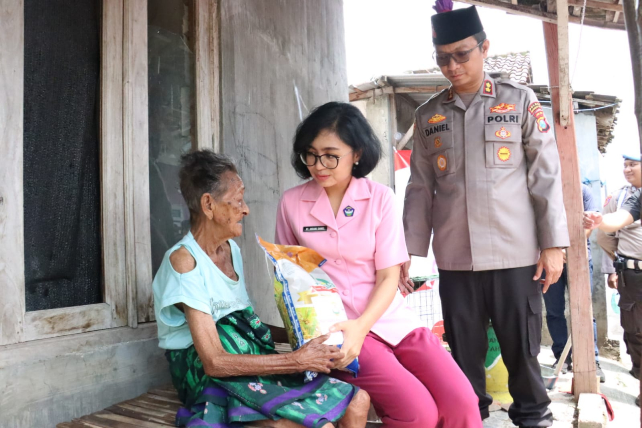 Ketua Bhayangkari Kota Mojokerto Ny. Andani Daniel didampingi Kapolres Mojokerto Kota AKBP Daniel S Marunduri memberikan paket sembako kepada warga Balongcangkring. (ist)