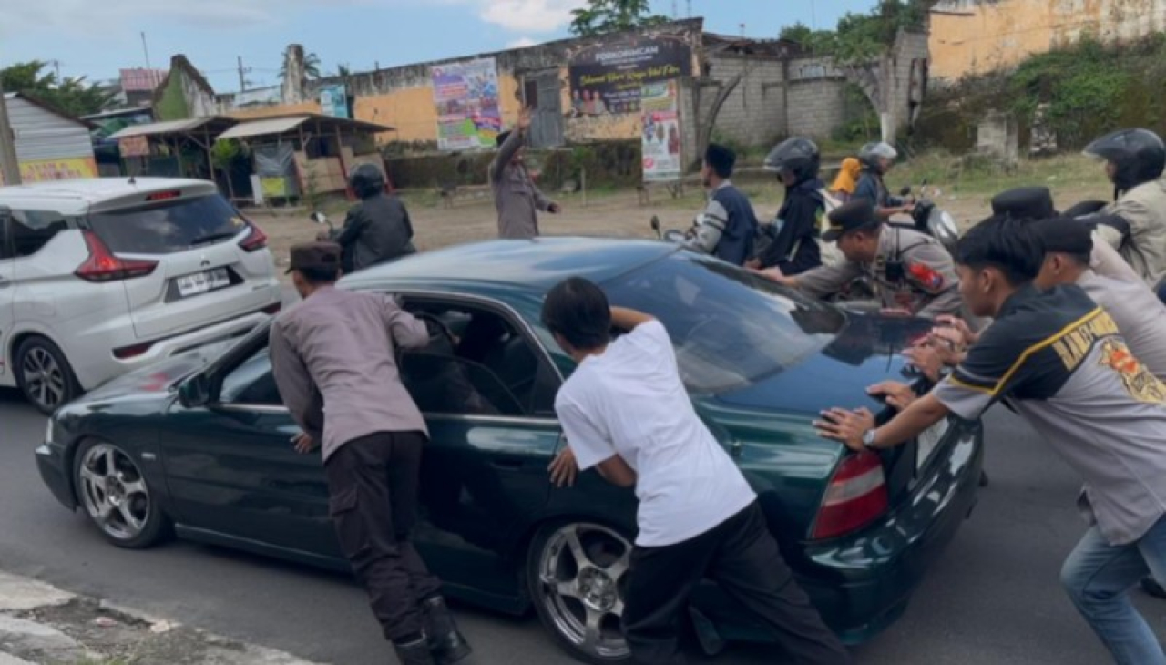 Petugas Polres Blitar dibantu warga mendorong mobil sedorang yang mogok saat mudik. (ist)