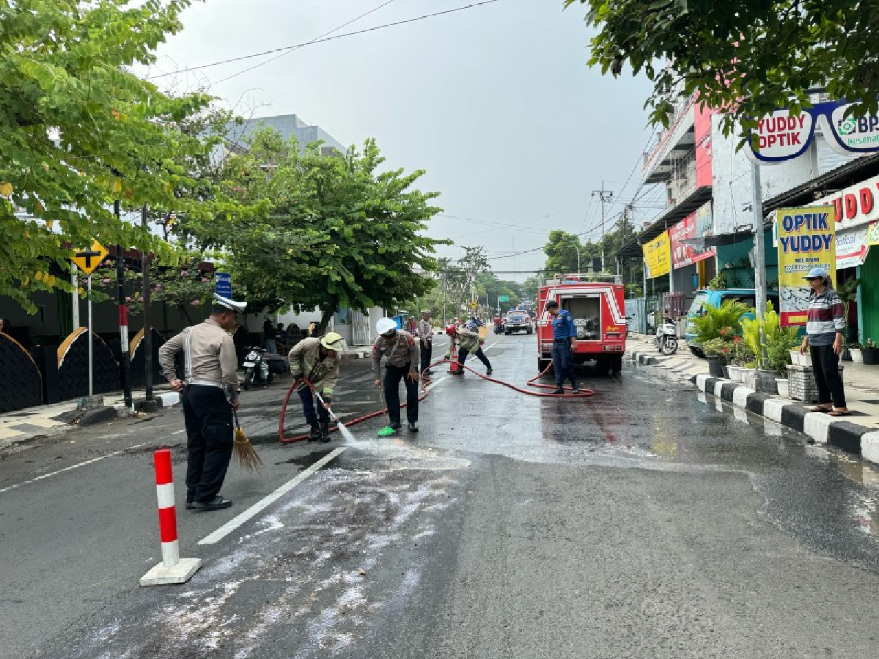 Anggota Polres Lamongan bantu bersihkan tumpahan solar di jalan. (ist)