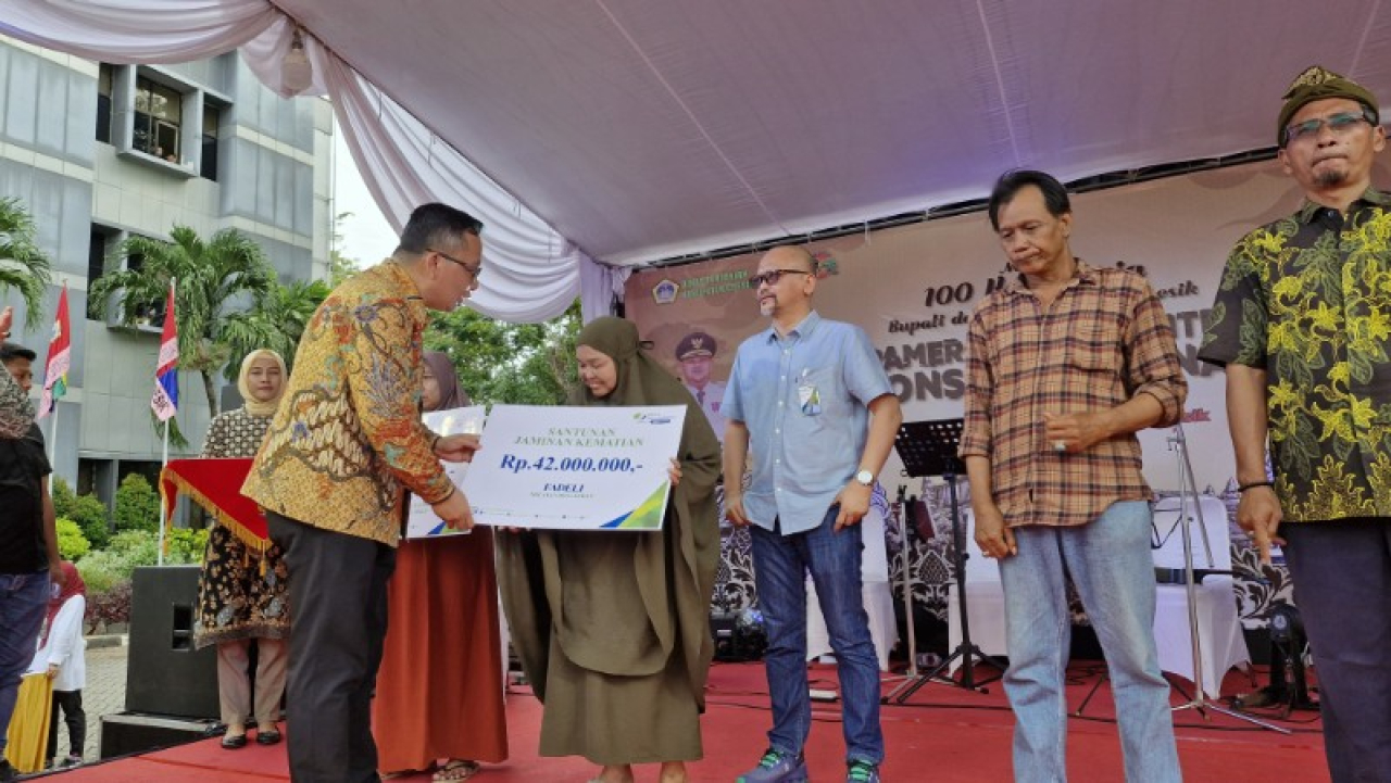 Plt Bupati Gresik dr Asluchul Alif di dampingi Kepala BPJS Ketenagakerjaan Gresik menyerahkan klaim meninggal secara simbolik. (ist)