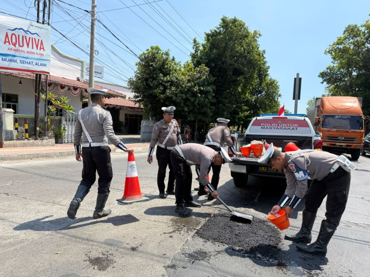 Anggota Polres Situbondo menambal jalan yang lubang (ist)