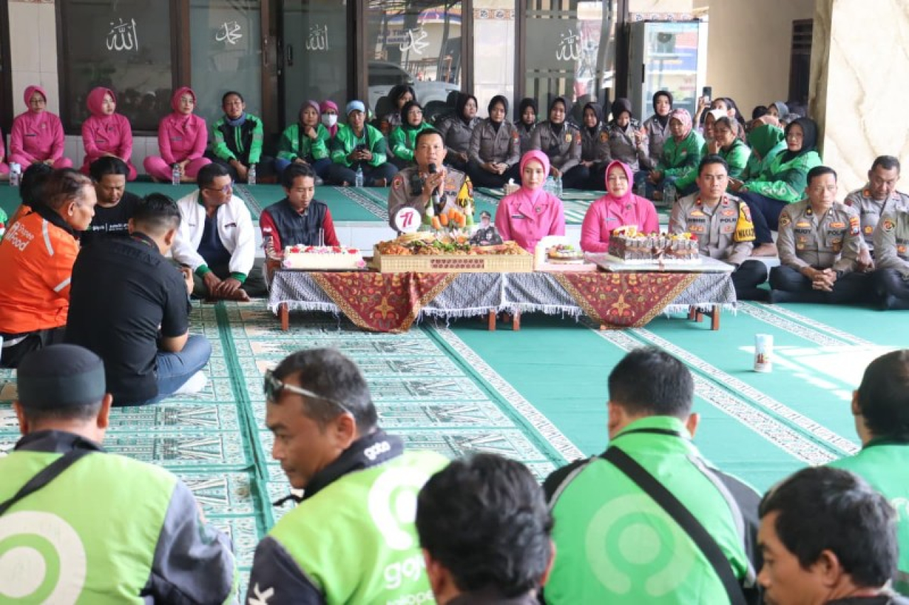 Kapolres Mojokerto Kota AKBP Herdiawan Arifianto potong tumpeng HUT Polwan bersama para ojol. (ist)