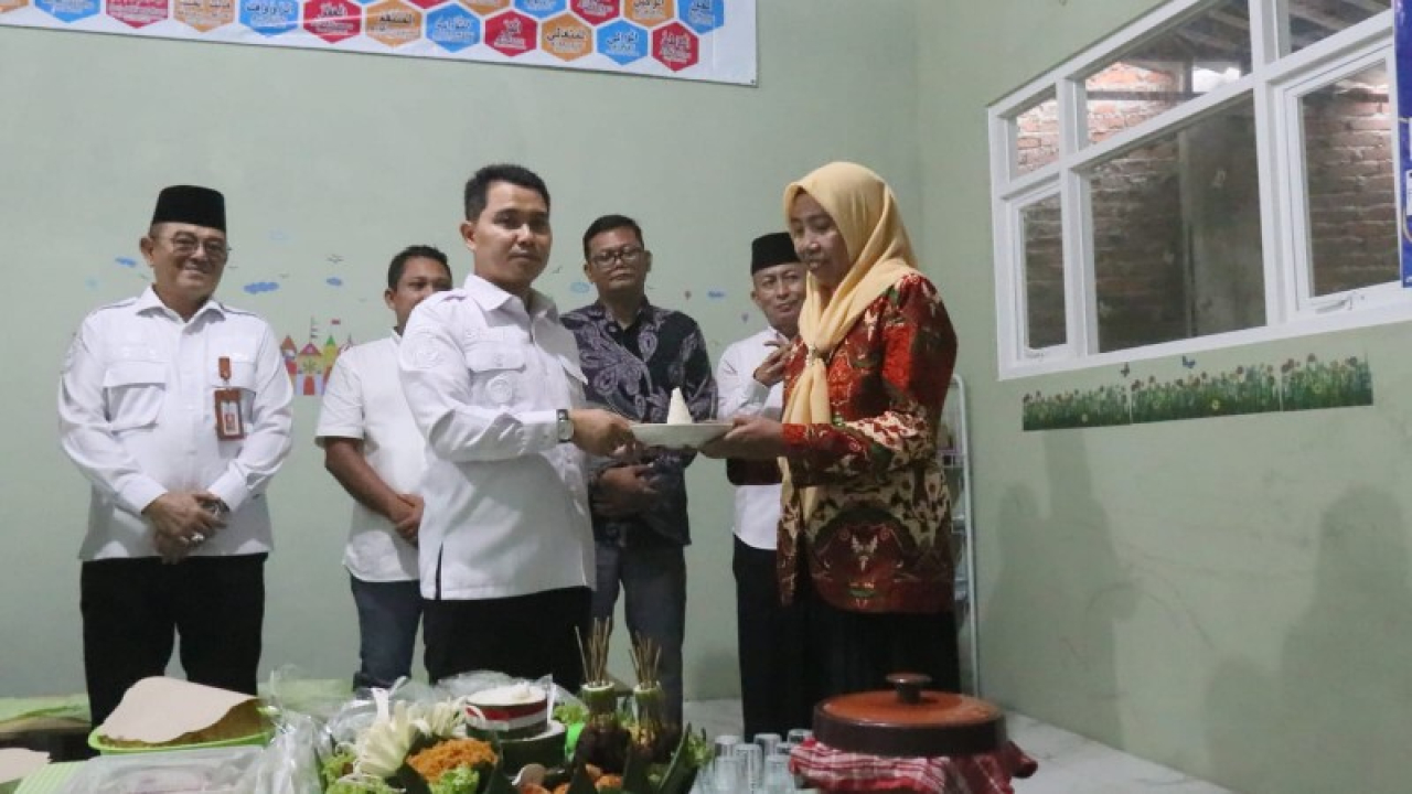 Gus Bupati memberikan potongan tumpeng kepada Kepala sekolah RA Darussalam. (ist)