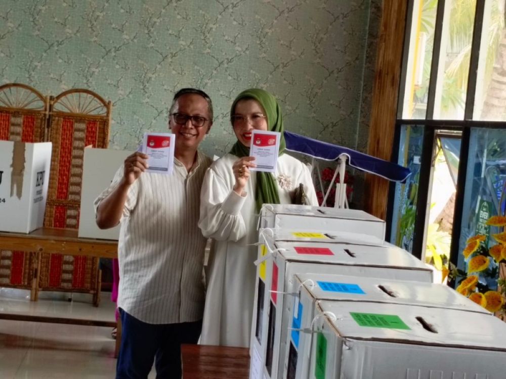 Arzeti didampingi suaminya, Aditya Setiawan menunjukkan kartu suara setelah mencoblos di TPS 09 Perum Istana Mentari Sidoarjo. (foto: zainul/B-news.id) 