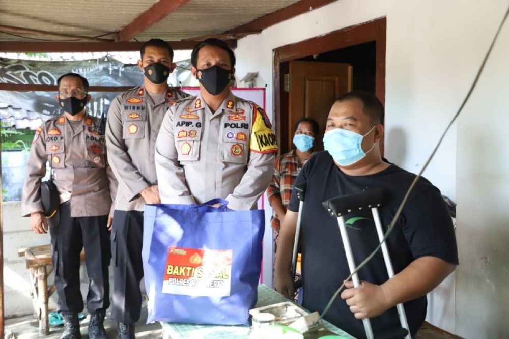 Penyandang difabel tersenyum bahagia usai menerima bantuan paket sembako dari Kapolres Mojokerto AKBP Apip Ginanjar. (Ist) 