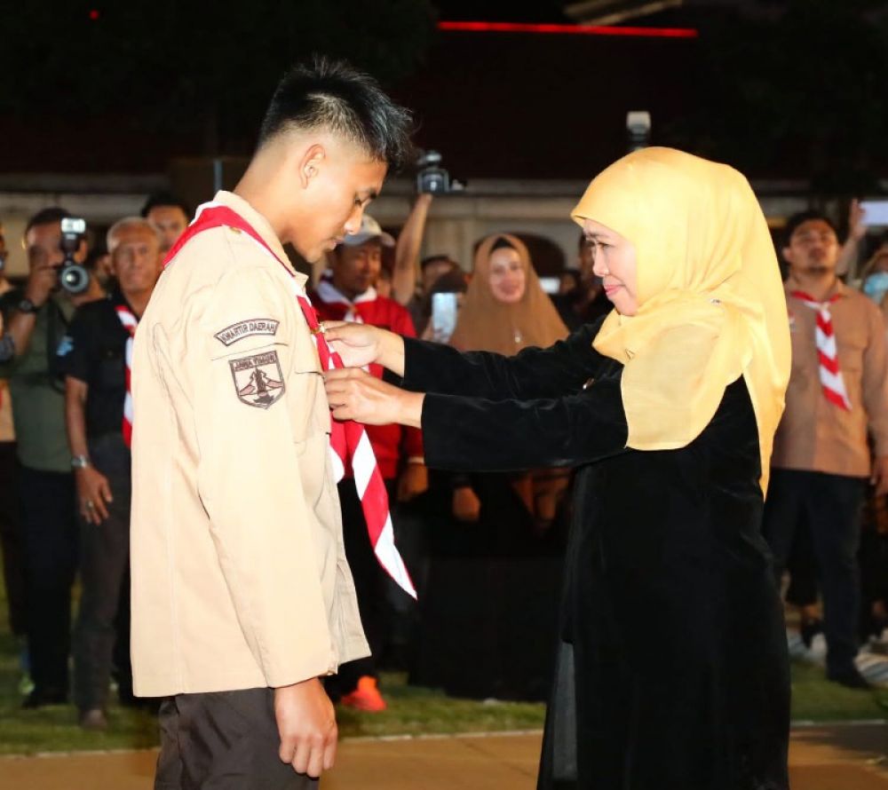 Gubernur Khofifah menyematkan topi dan dasi pramuka kepada Mario Aji saat pelantikan jadi Duta Pramuka Jatim. (Ist) 