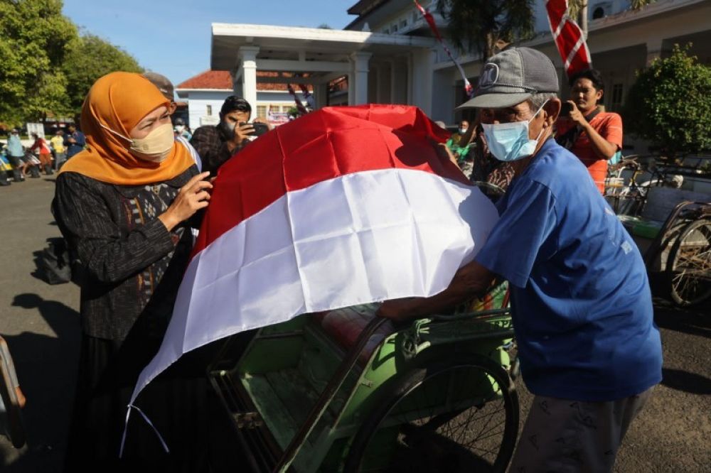 Gubernur Khofifah membagikan bendera Merah Putih kepada tukang becak di Pamekasan. (Ist) 