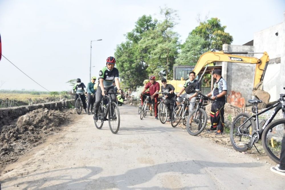 Bupati Gus Muhdlor sidak proyek jalan betonisasi dengan berkeliling bersepeda onthel. (Ist) 