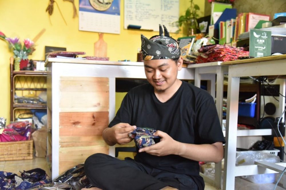 Hanif, pelaku UMKM dari Rahayu Arts Design Griya Nirwana Sumorane Candi ini sedang membuat kerajinan udeng. Himbauan pemkab Sidoarjo penggunaan produk UMKM lokal ini mampu meningkatkan perekonomian keluarga dan masyarakat sekitar. (Ist) 