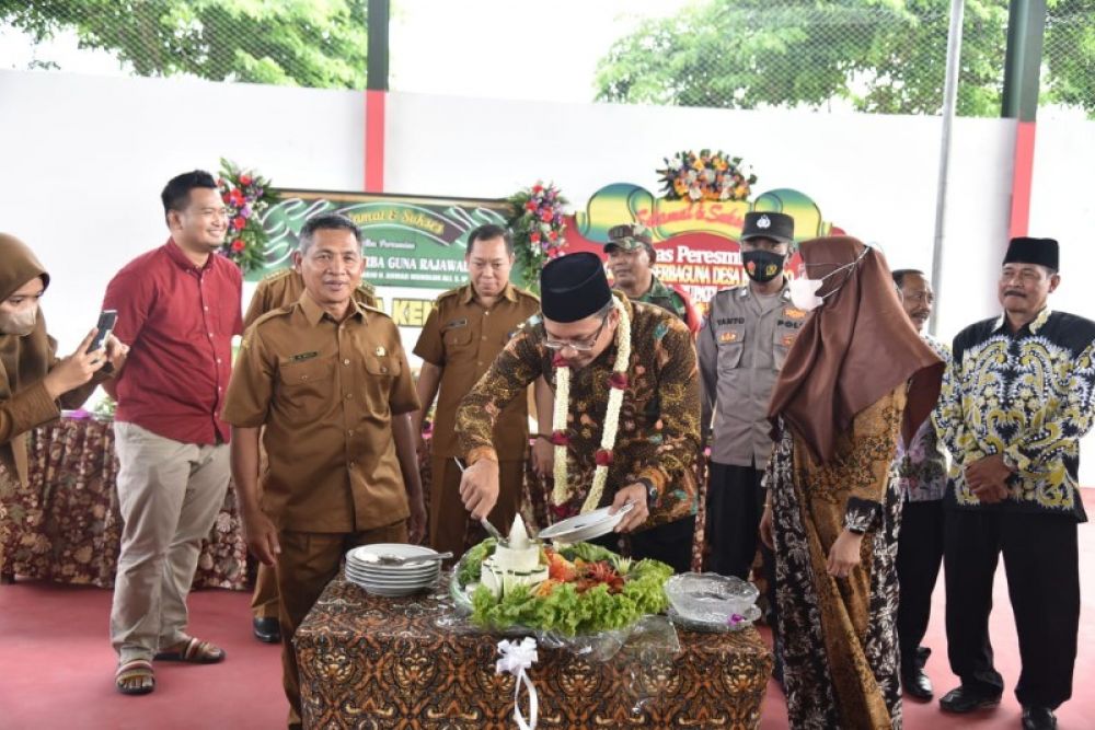 Bupati Gus Muhdlor meresmikan gedung serbaguna ditandai dengan prmotongan untaian bunga melati dan pemotongan tumpeng disaksikan Kades Kenongo, Tulangan, M Husin. (Ist) 
