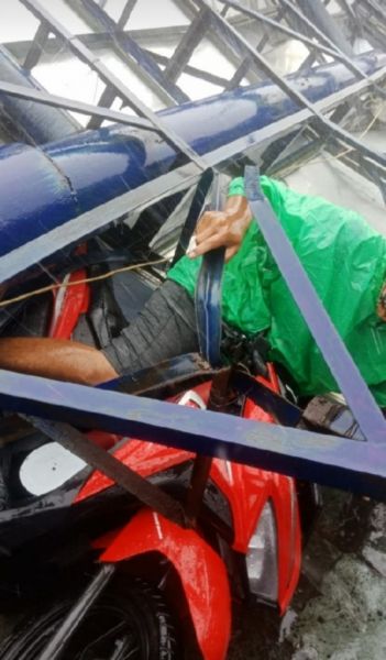 Seorang pengendara sepeda motor Honda Vario tertimpa papan reklame raksasa yang roboh di wilayah Aloha. (Ist) 