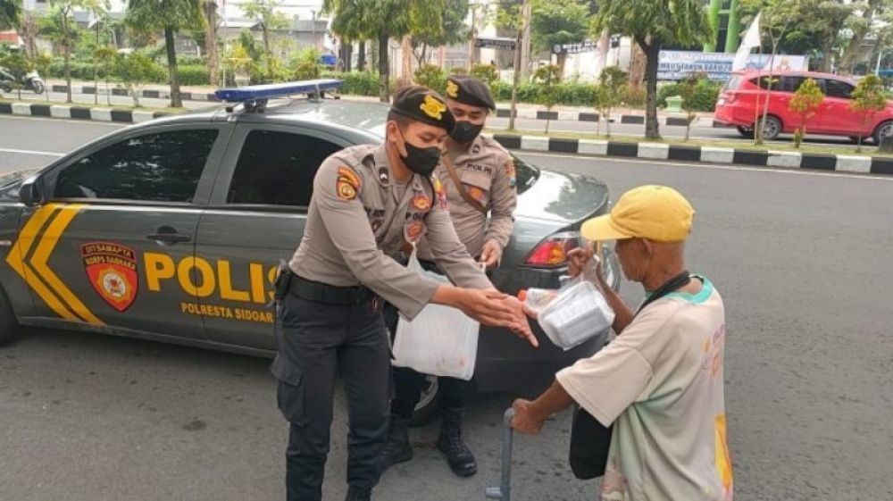 Anggota Samapta Polresta Sidoarjo saat membagikan nasi kepada warga di jalan. (Ist) 
