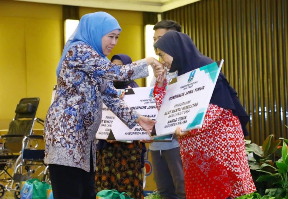 Gubernur Khofifah secara simbolis menyerahkan bantuan kepada keluarga penerima manfaat dalam program PKH Plus. (Ist) 