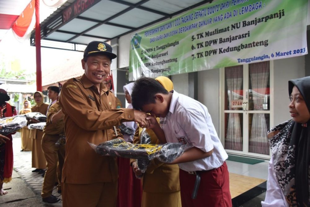 Kepala Dinas Pendidikan zkabupaten Sidoarjo Tito Adi secara, simbolis menyerahkan bantuan sepatu boots kepada siswa yang terdampak banjir. (Ist) 